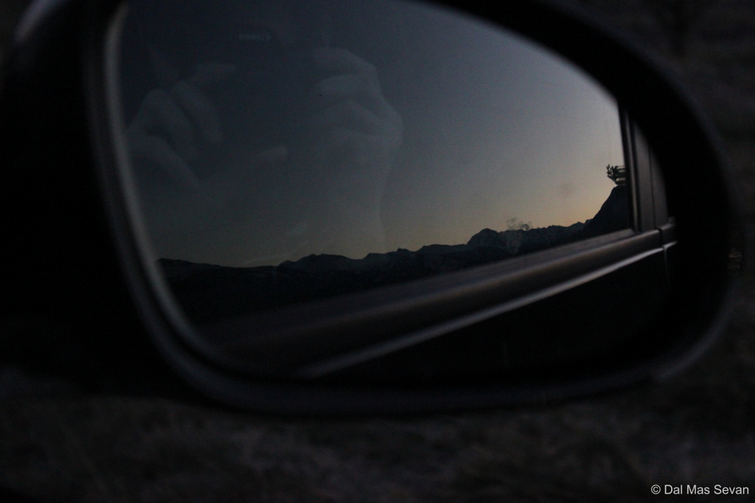 Rétroviseur de voiture reflétant le photographe et la montagne au crépuscule